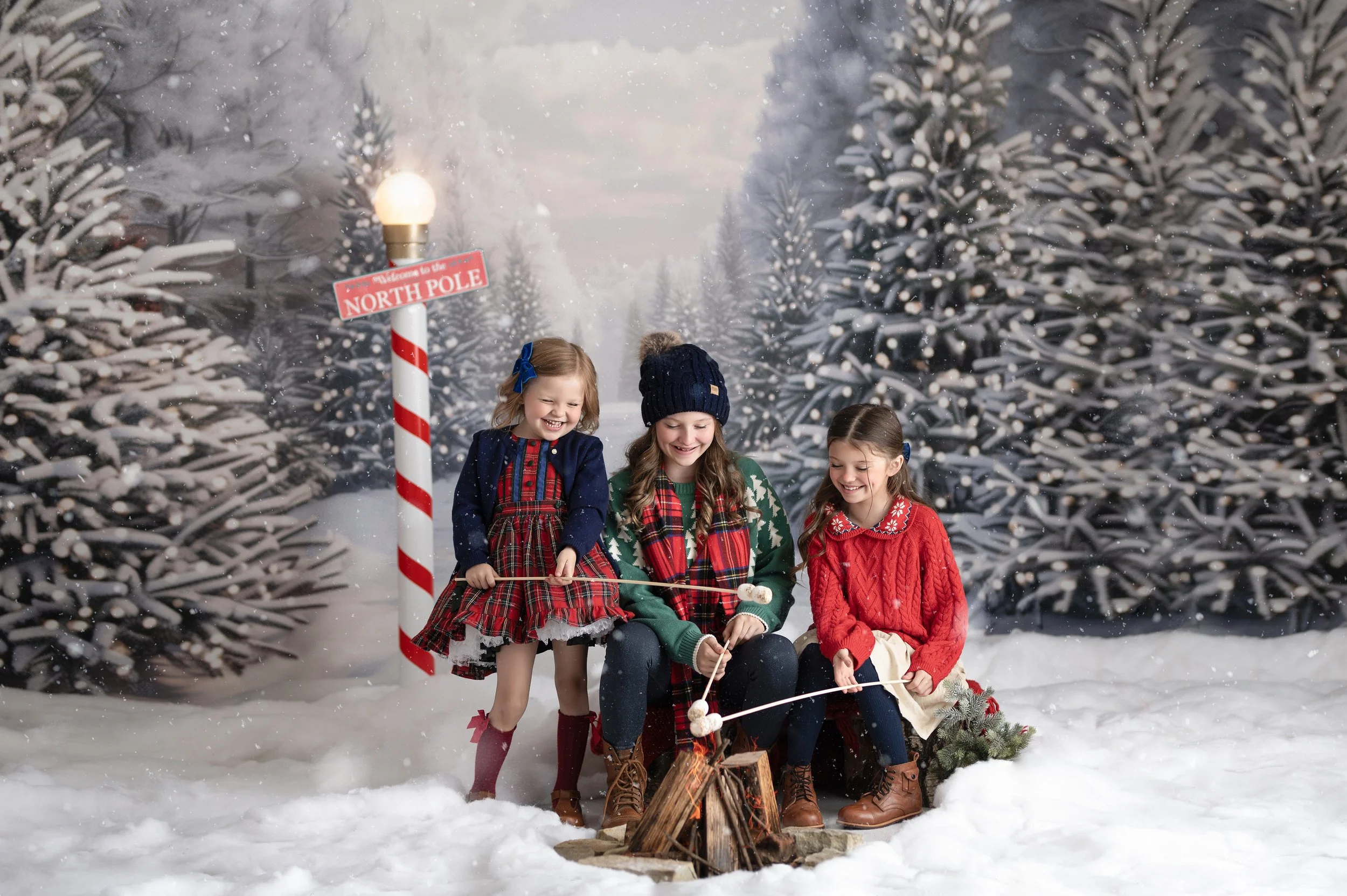 Three children posing together in a snowy outdoor-inspired Christmas photography set.