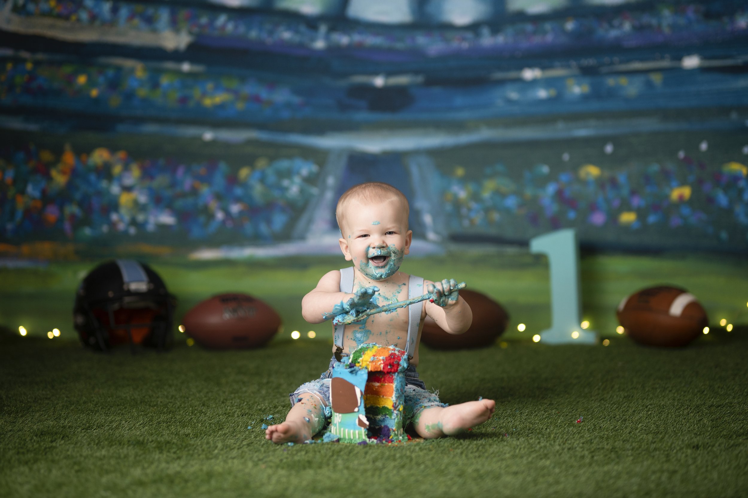 Baby boy celebrating his first birthday in a football-themed Cake Smash photography set.