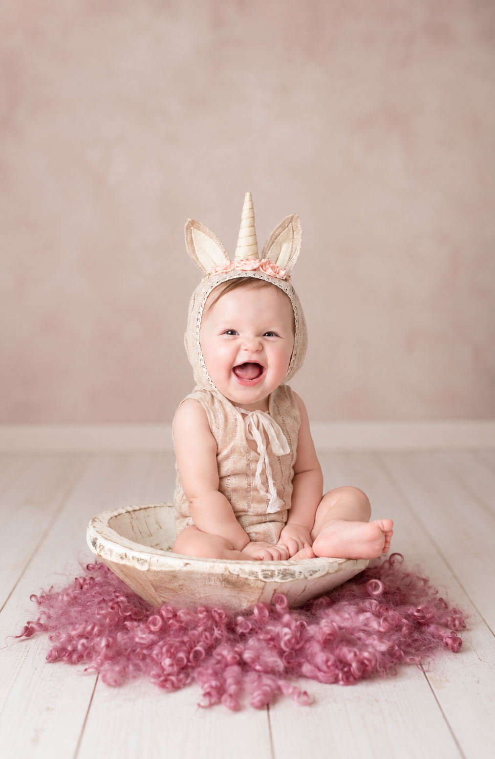 Smiling baby wearing a unicorn bonnet during a first milestone photography session in Millersville, Maryland.