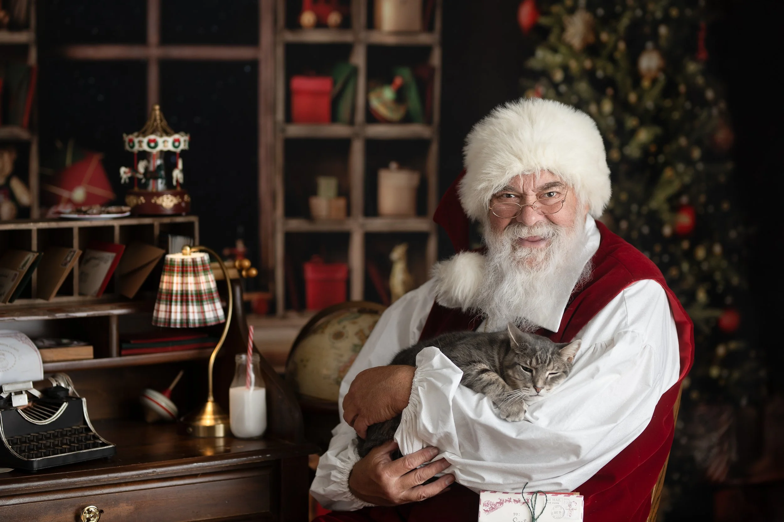 Santa holding a cat in a traditional Christmas photography set at Mary Purdy Photography.