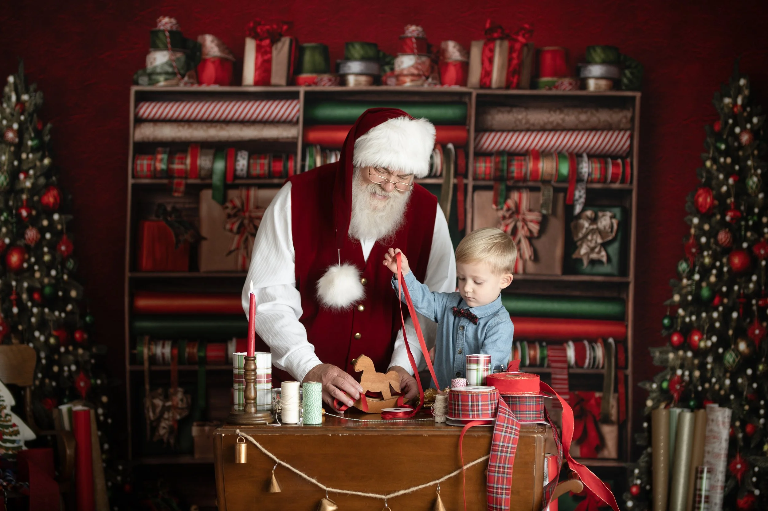 Santa sharing a playful moment with a child in a festive Christmas workshop photography set.
