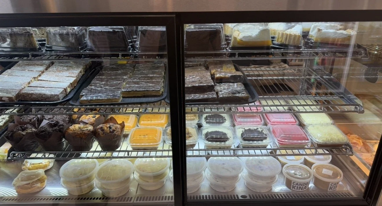 Display case with various baked goods, including cakes, muffins, and desserts, in a bakery.