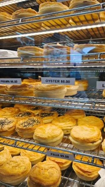 Bakery display with various pastries and pies on metal shelves.