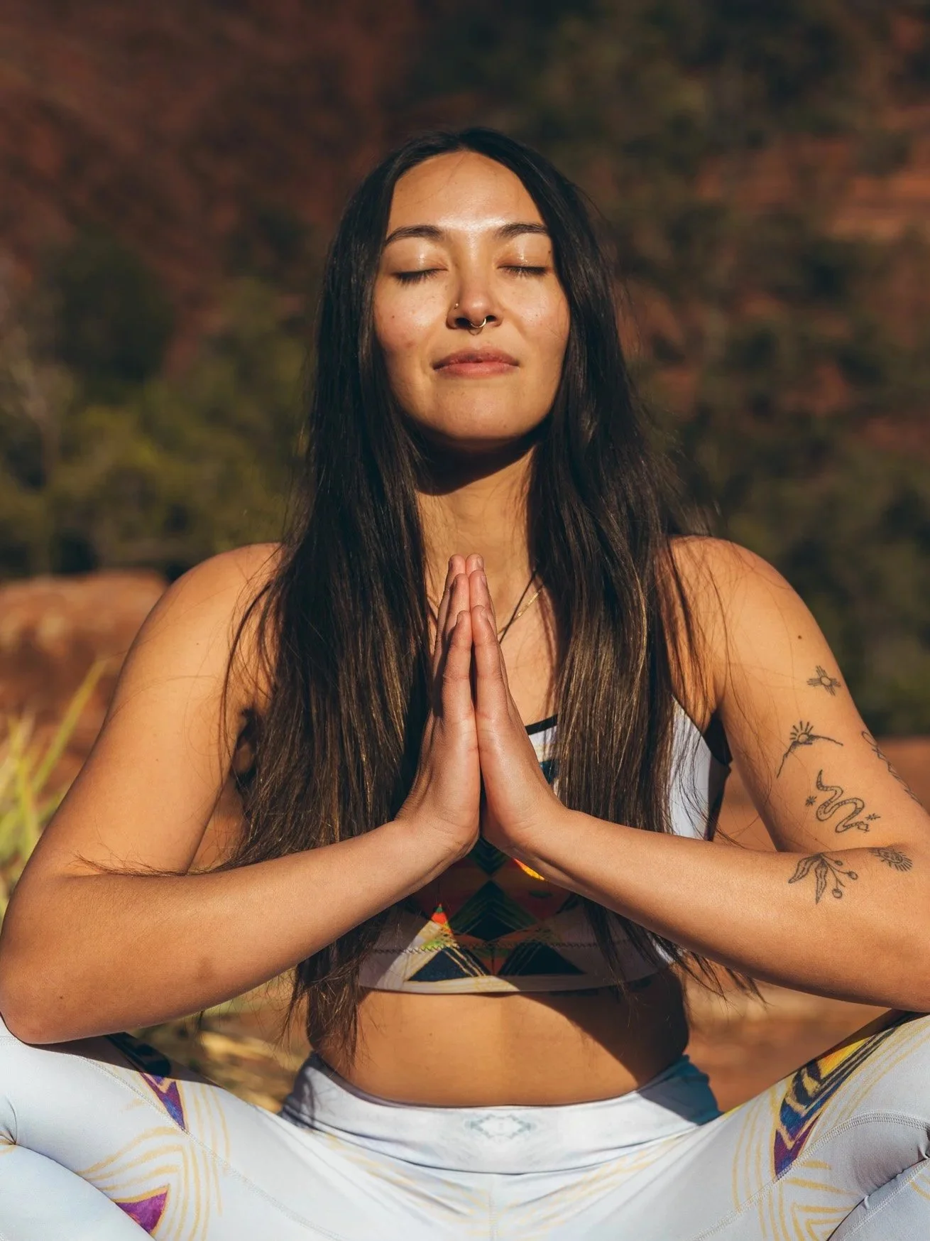 A woman practicing yoga outdoors with closed eyes and hands in prayer position.