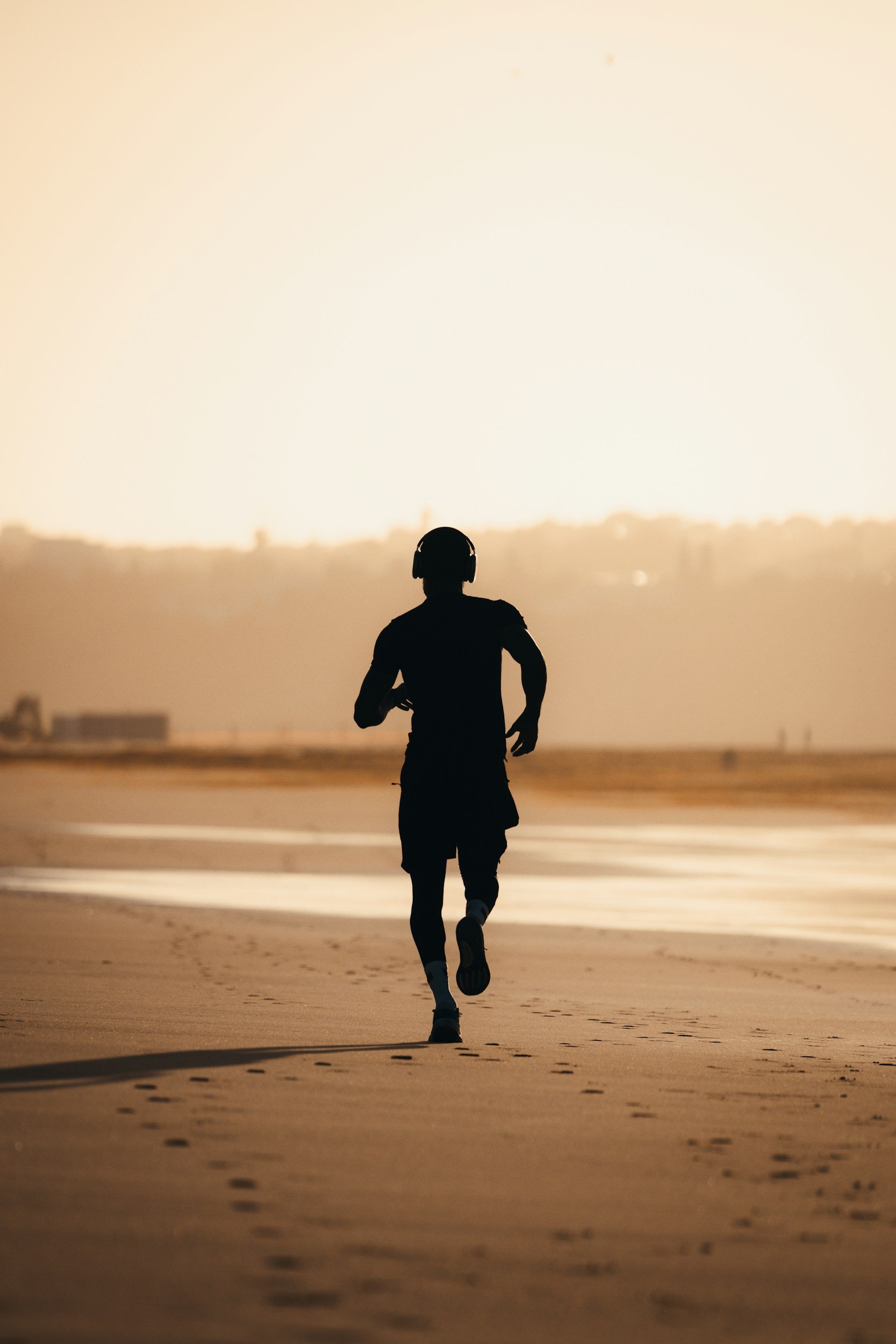 Silhouette of a person running on a beach at sunset or sunrise.