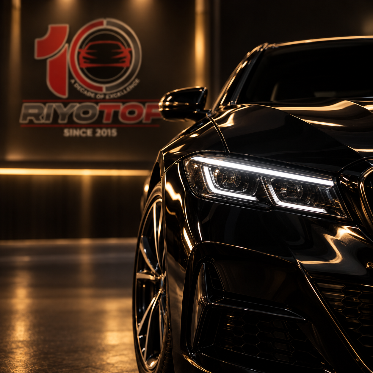 Close-up of a shiny black luxury car in a showroom with a Ryotoff banner in the background.