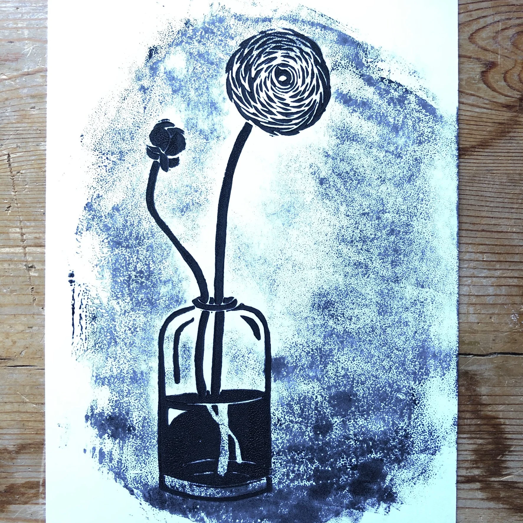 Stencil art of a wine bottle with a sip silhouette, a flower, and a spiral flower in a bottle, painted in black on white paper with blue spray paint background.