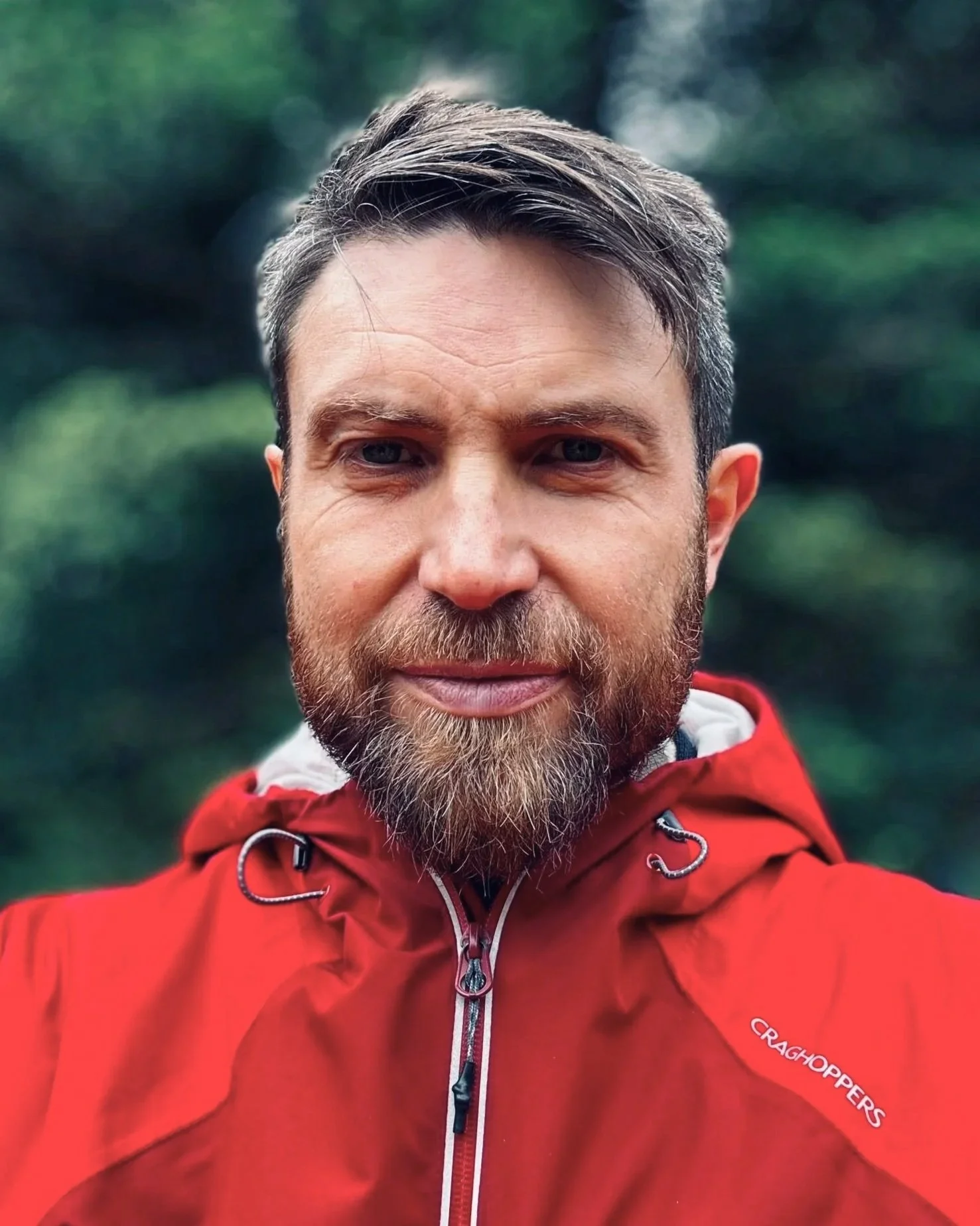 Close-up of Rob Brown, outdoors with blurred trees in the background.