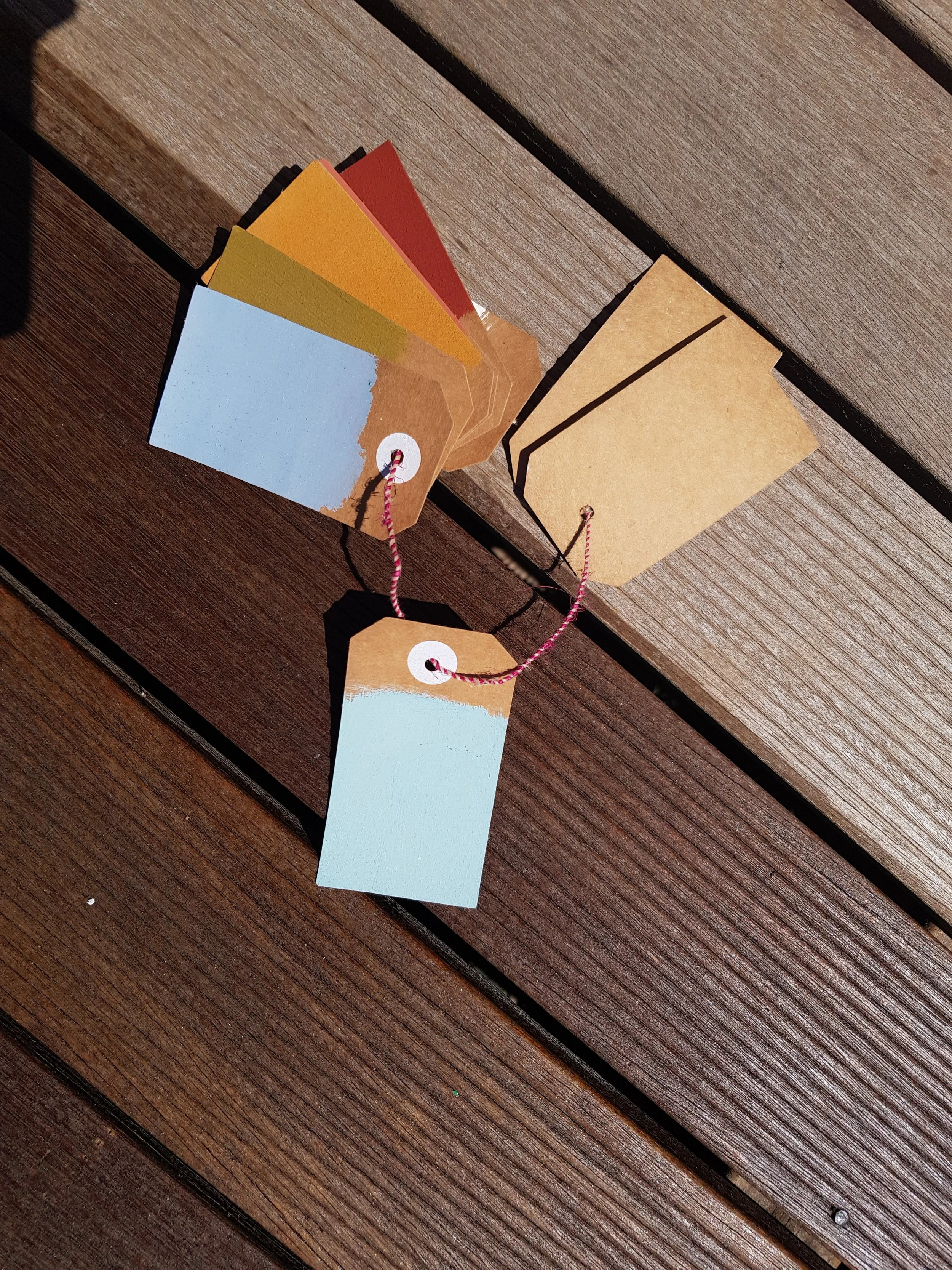 Colorful paper tags with string on wooden surface.