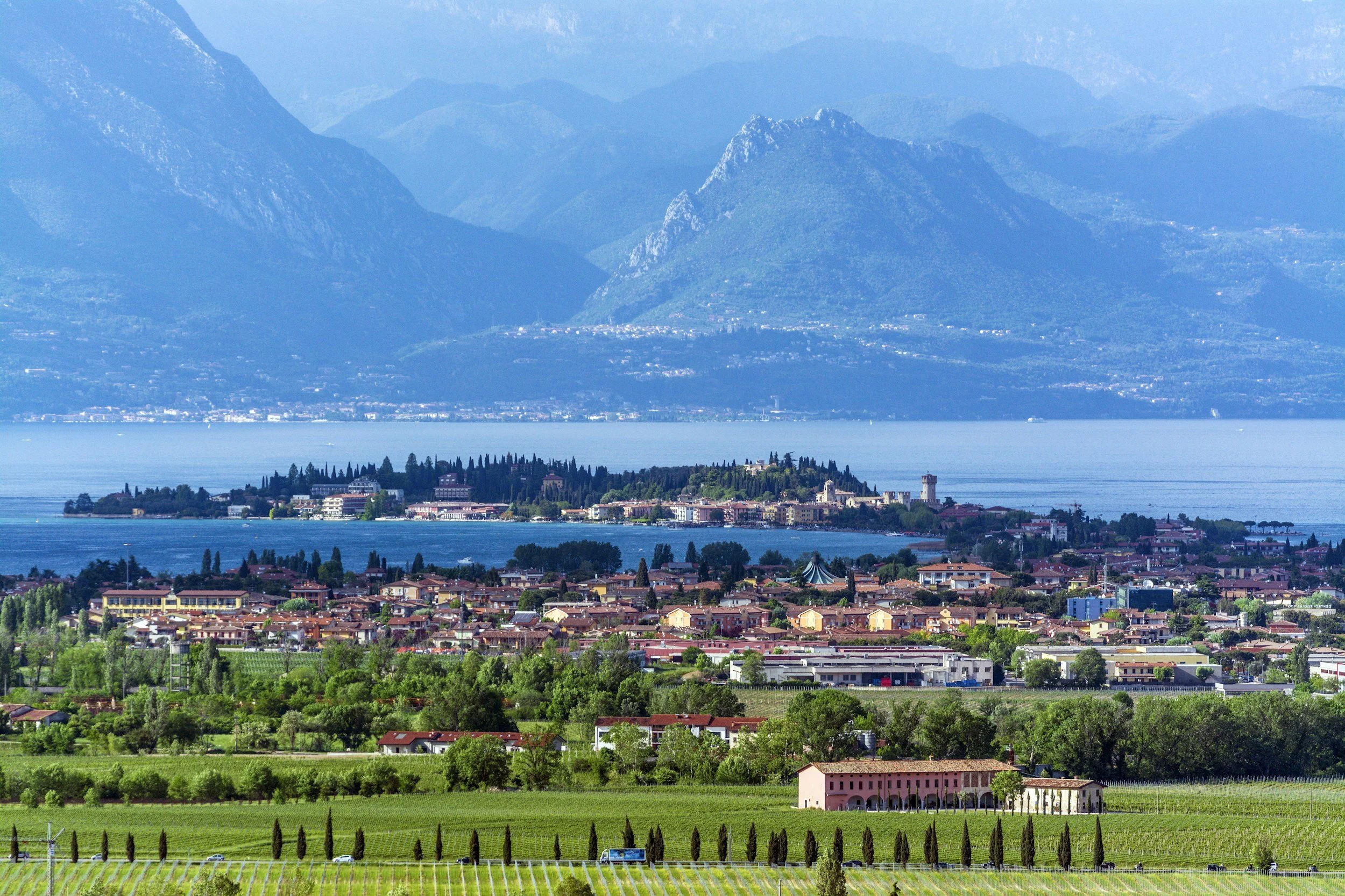 Veduta del Lago di Garda con un paese sulla riva e le montagne sullo sfondo