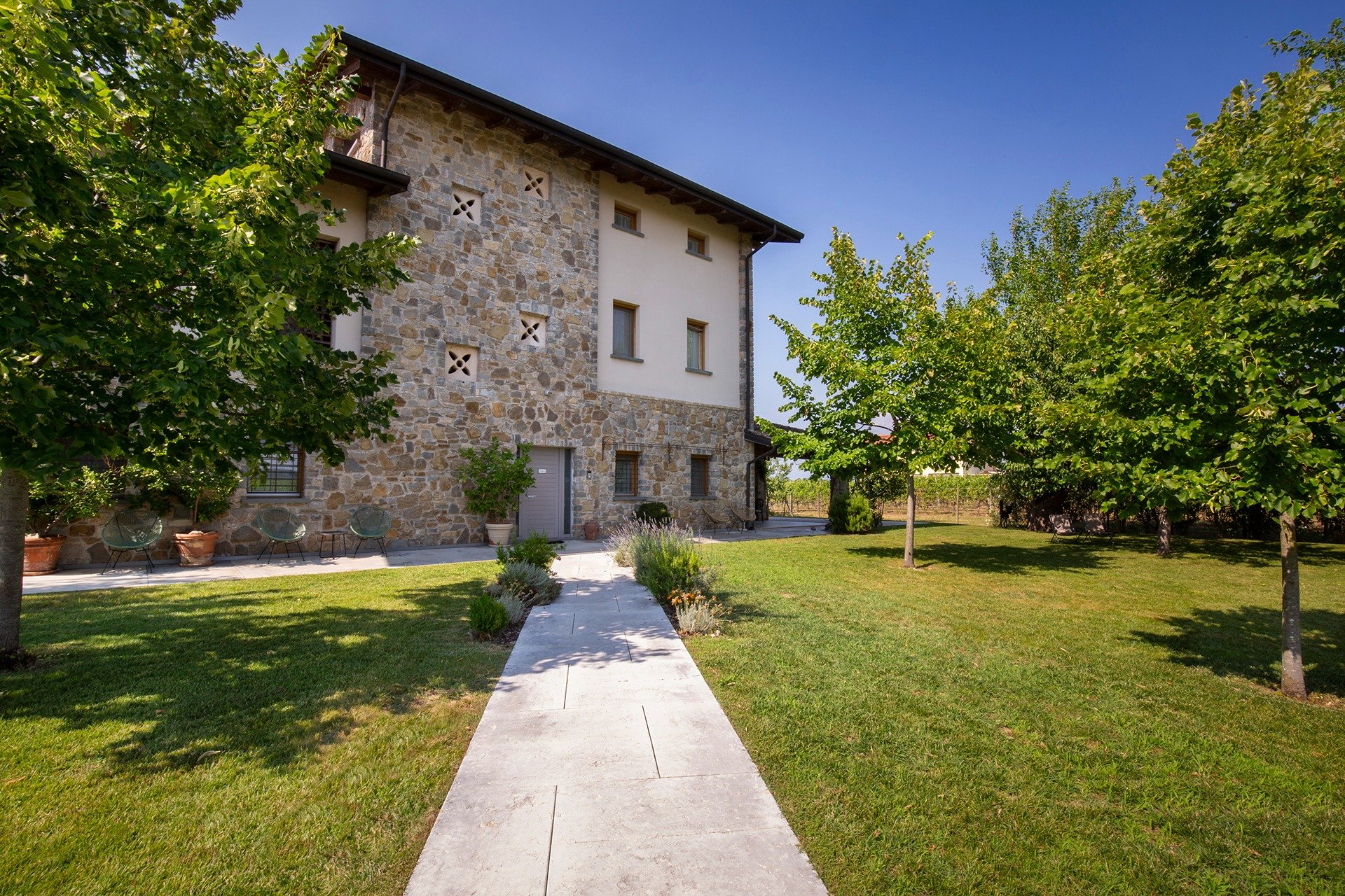 Il casale in pietra di Massoni Wine Relais con il giardino e il vialetto d'ingresso