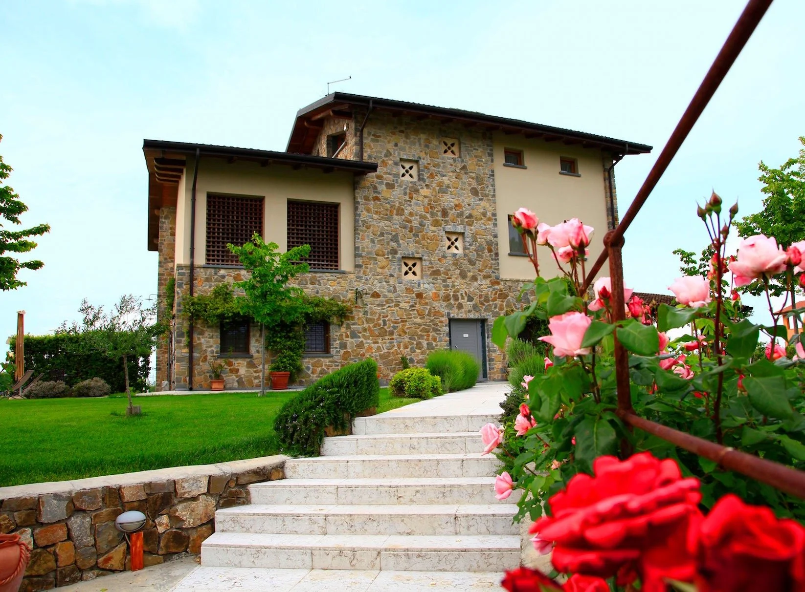 The stone farmhouse with its entrance steps and roses in bloom