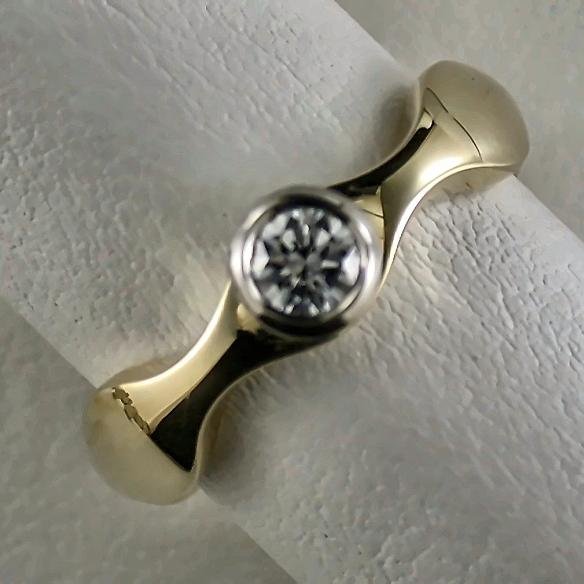 Close-up of a ring with a large, round, clear gemstone set in a gold band.