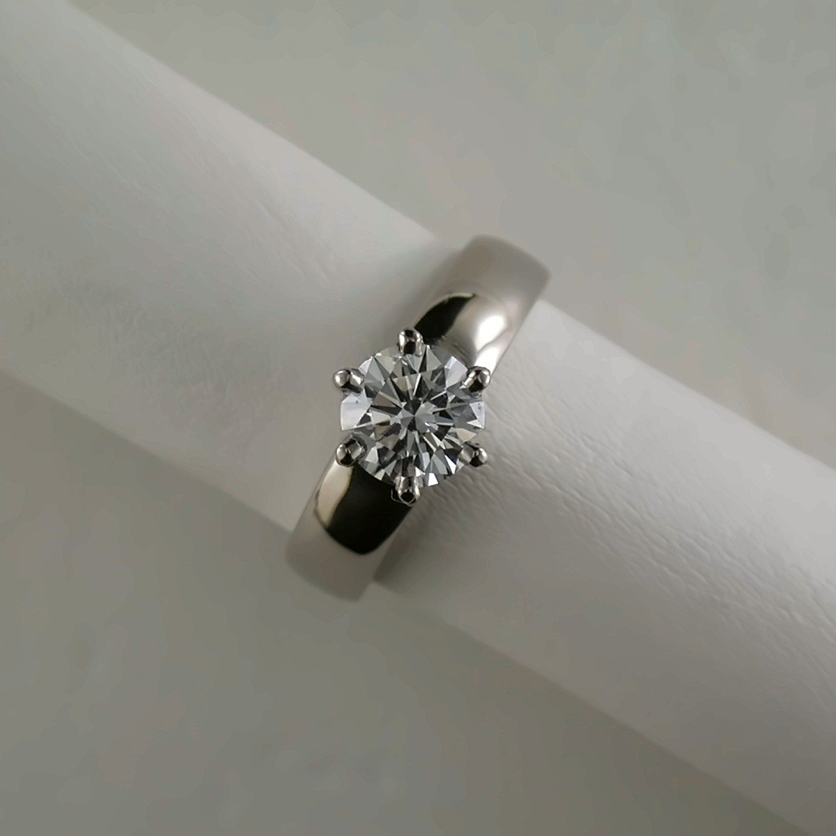 Close-up of a diamond solitaire engagement ring with a white gold band, displayed against white background.