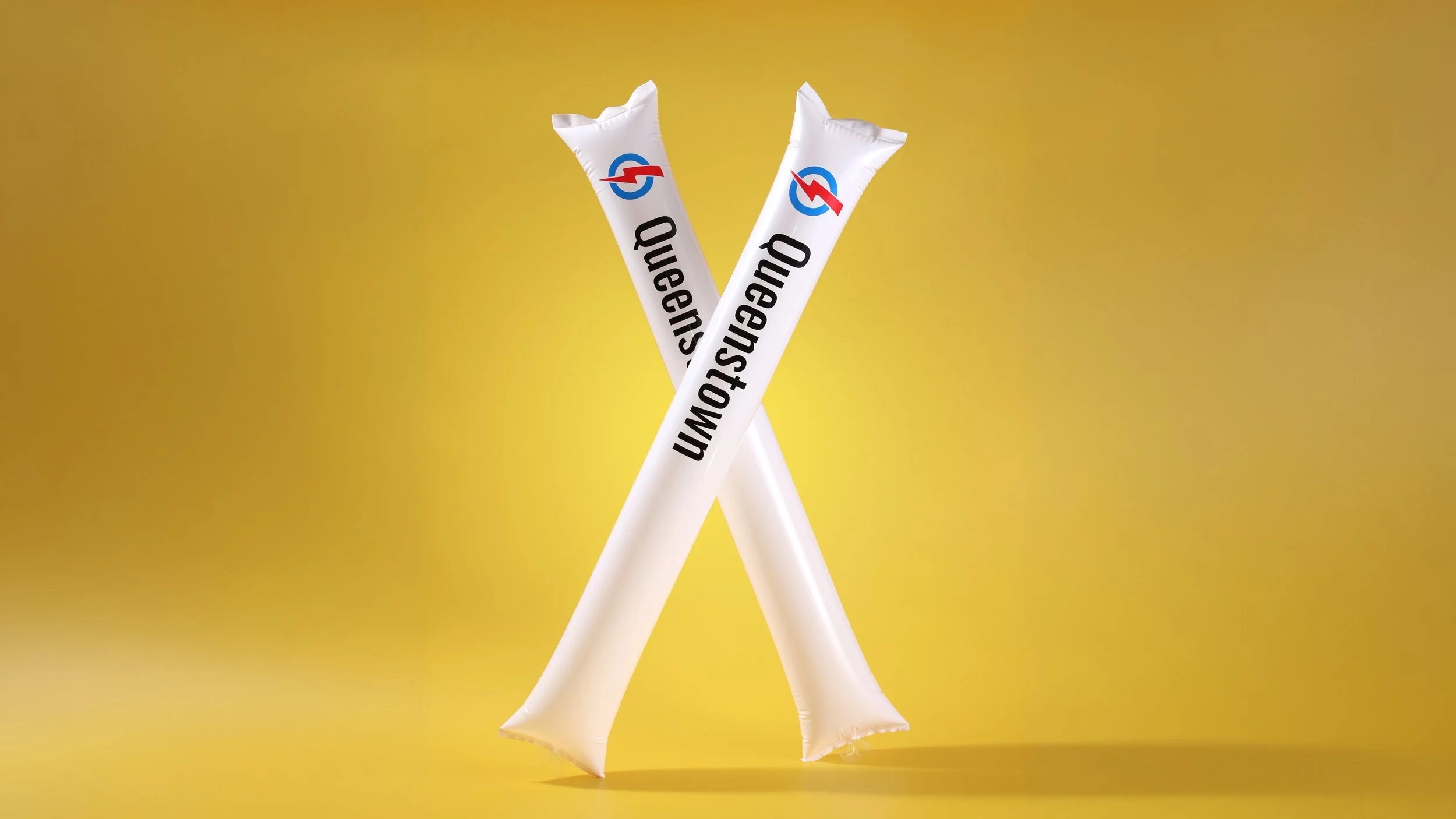 Pair of white inflatable cheering sticks crossed upright, printed with a logo and name down each stick