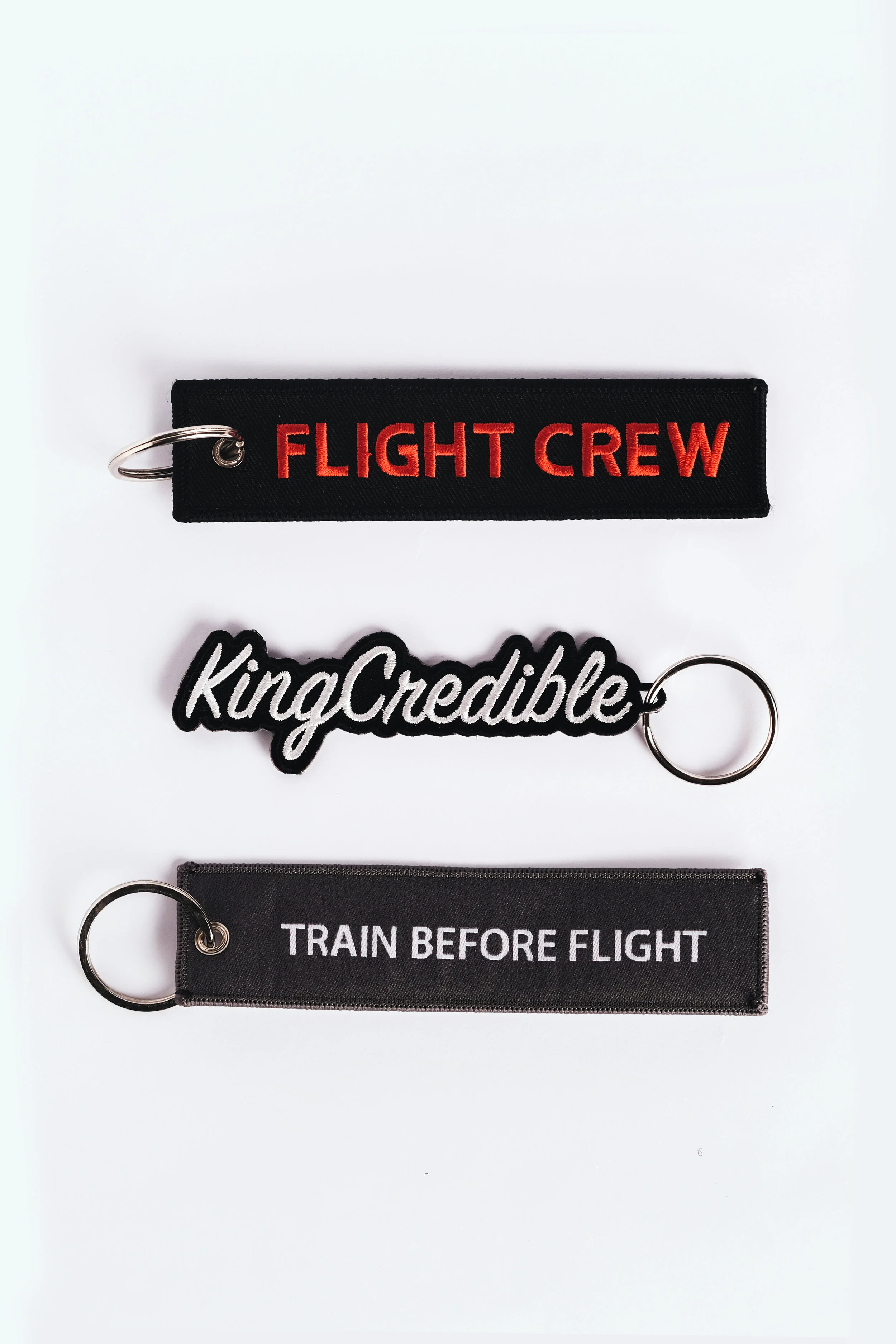 Three embroidered keychain tags reading Flight Crew, KingCredible and Train Before Flight