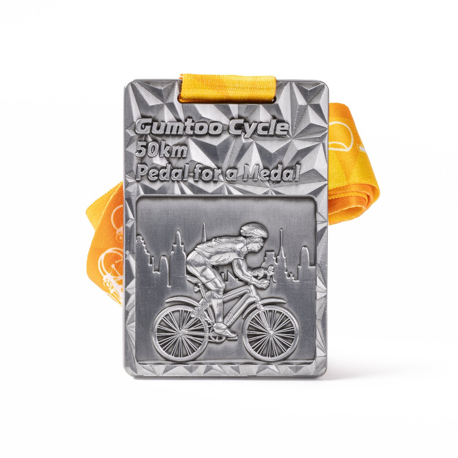 Rectangular 3D medal with a cyclist and skyline in raised relief, on an orange ribbon