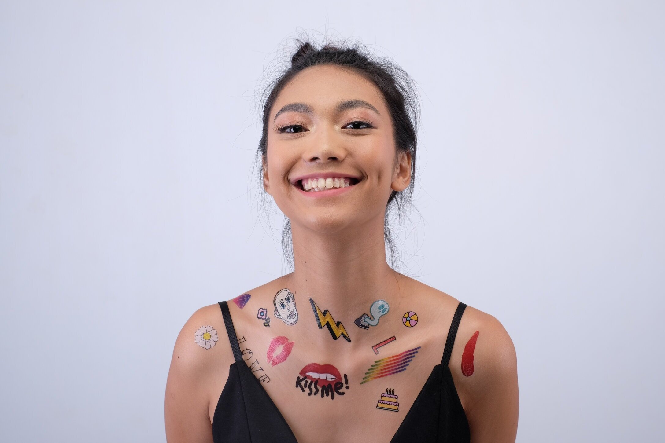 Woman wearing an array of brightly coloured custom temporary tattoos across her shoulders and chest