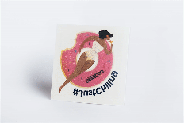 Pink cosmetic glitter temporary tattoo on its backing sheet, catching the light as it turns