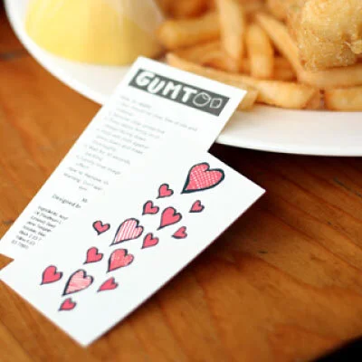 Individually cut heart temporary tattoos beside a printed order form on a wooden table