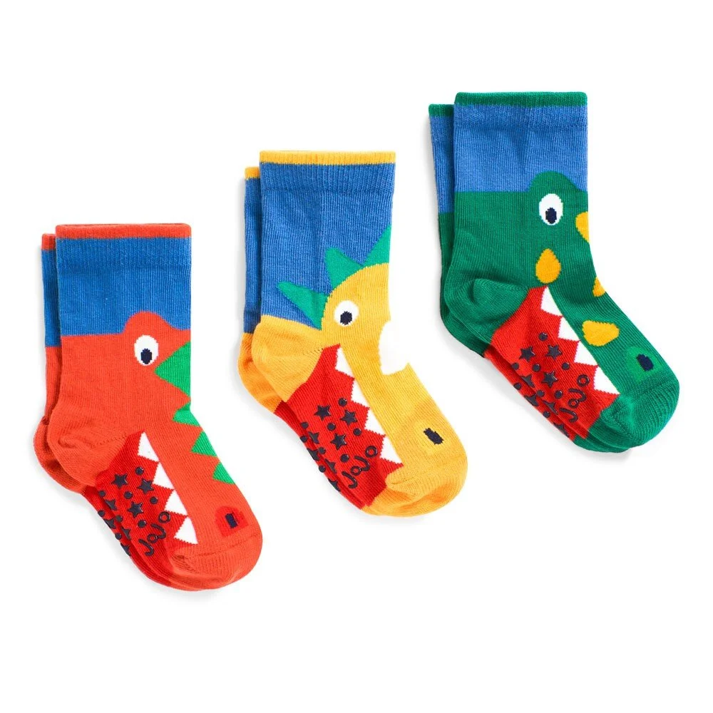 Three pairs of kids socks knitted with orange, yellow and green dinosaur character designs