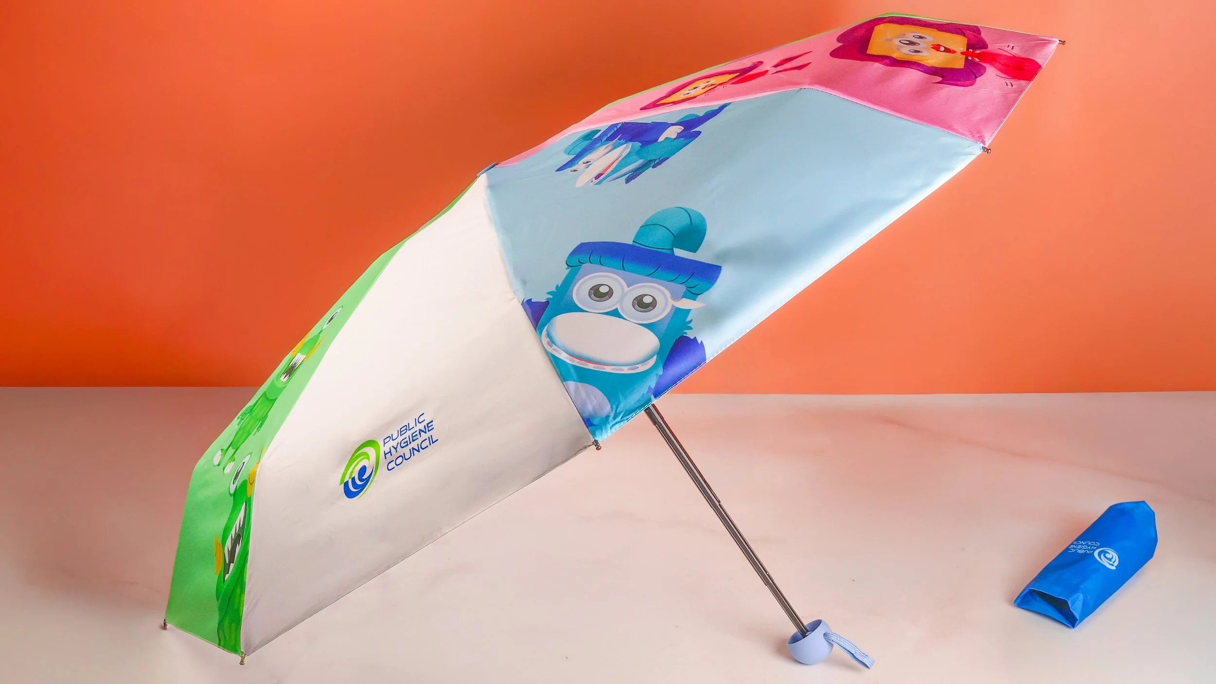 Public Hygiene Council custom umbrella printed with full-colour cartoon characters, shown with its pouch