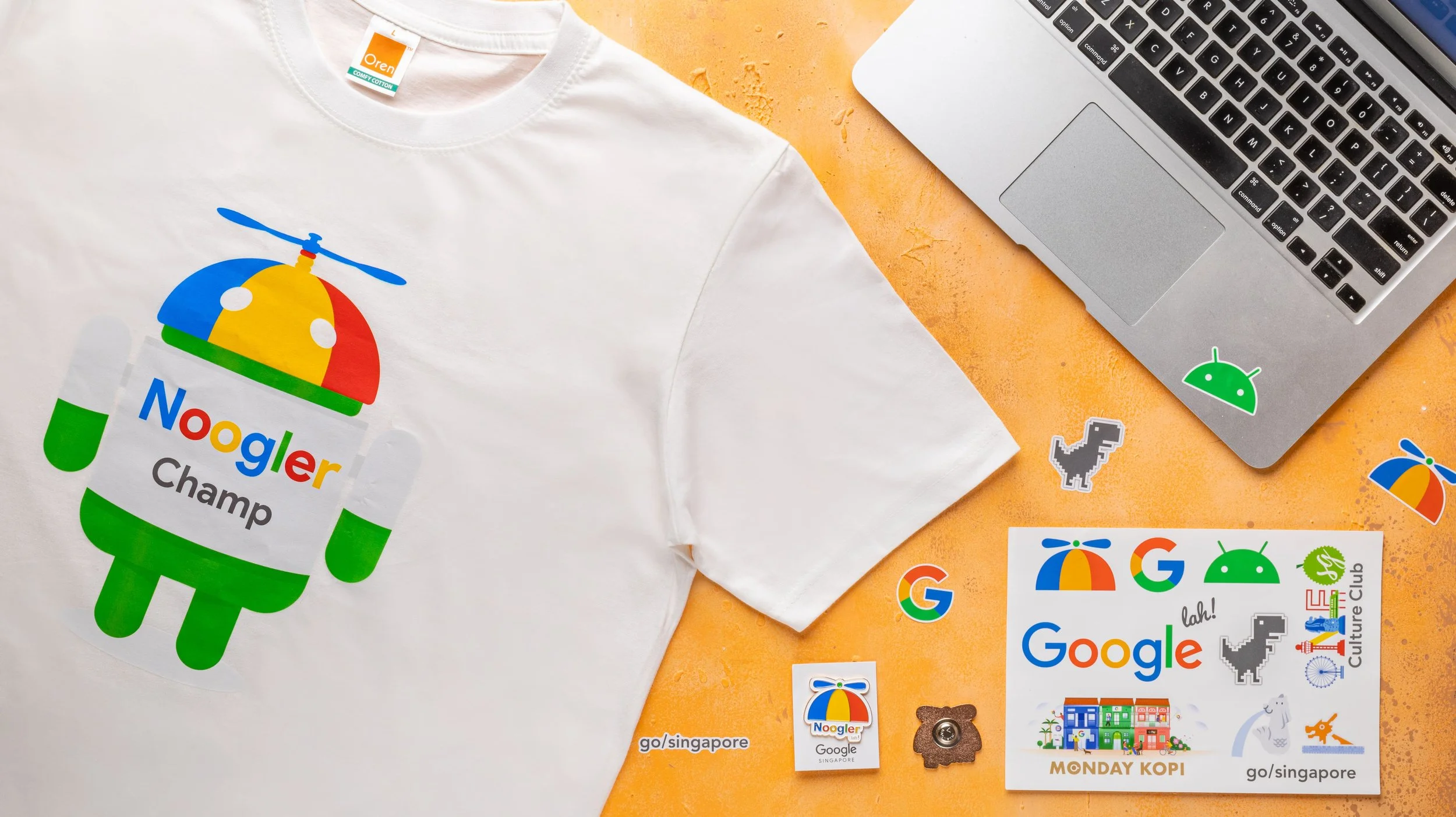 Google Noogler onboarding kit with a printed t-shirt, enamel pin and sticker sheet