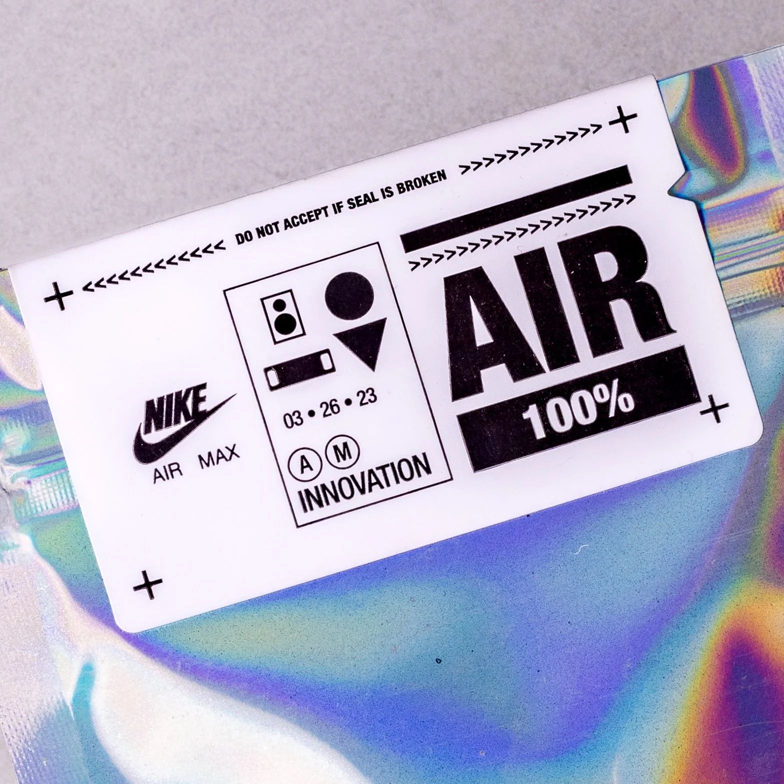 Close view of the Nike Air Max AIR 100% label sealing a holographic charm pouch