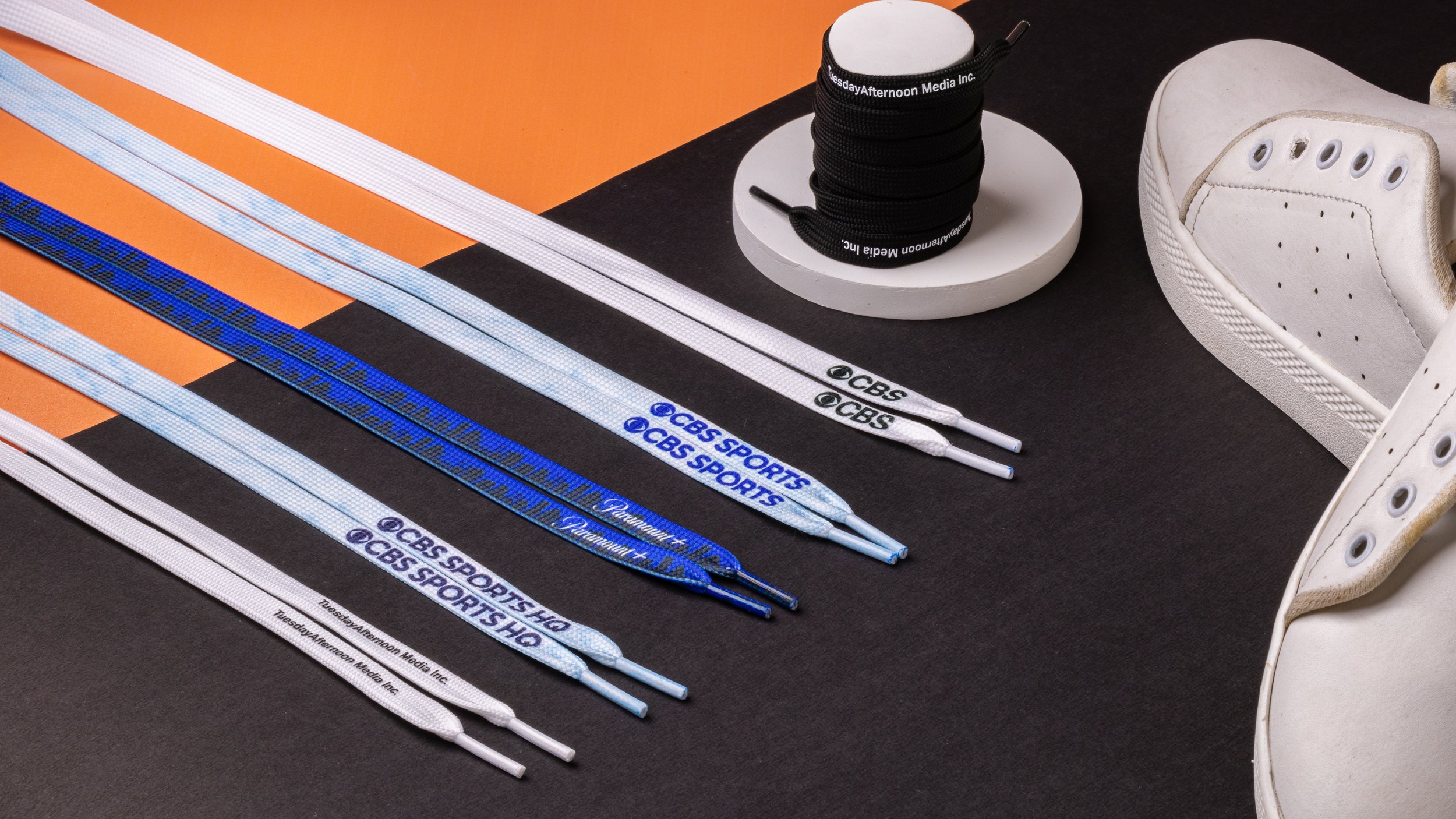 Six pairs of printed logo shoelaces for a media group, in white, pale blue, blue and black