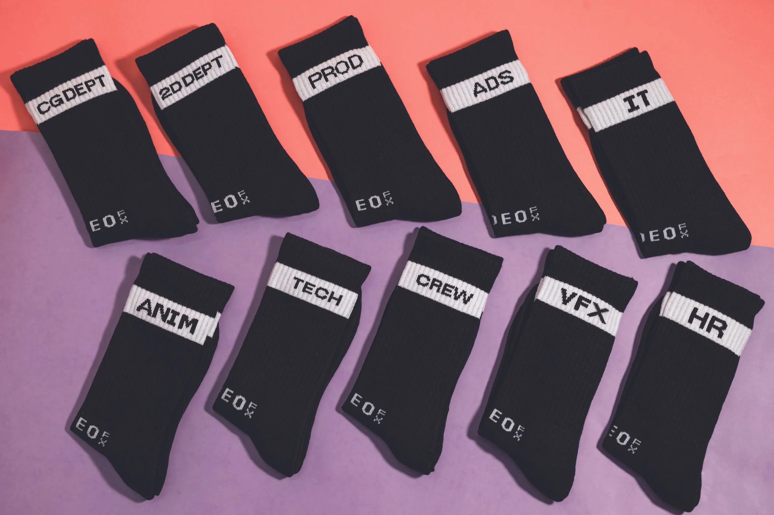 Ten pairs of black custom crew socks, each knitted with a different department name