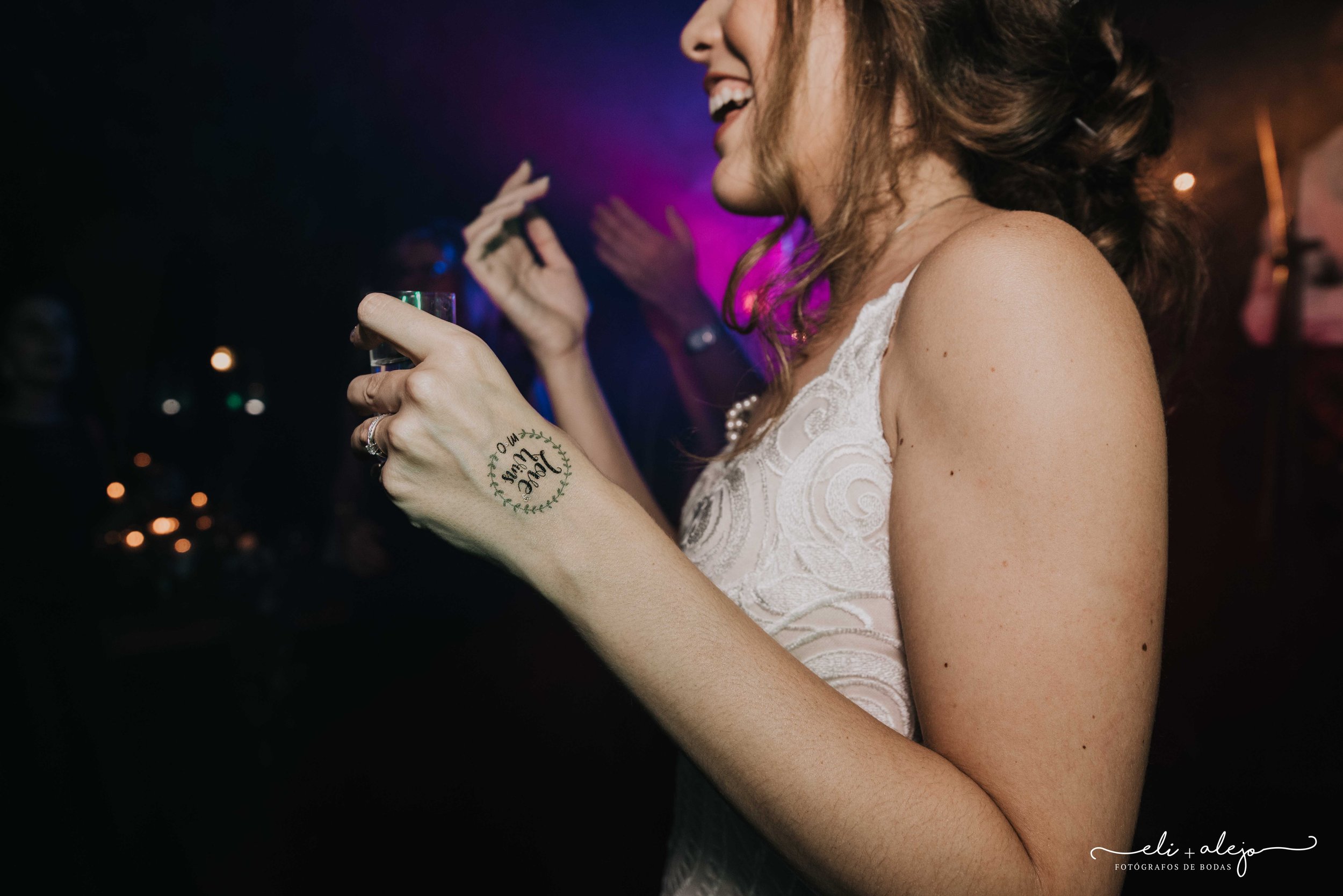Bride on the dance floor wearing a personalised wedding temporary tattoo with the couple's names in a leaf wreath