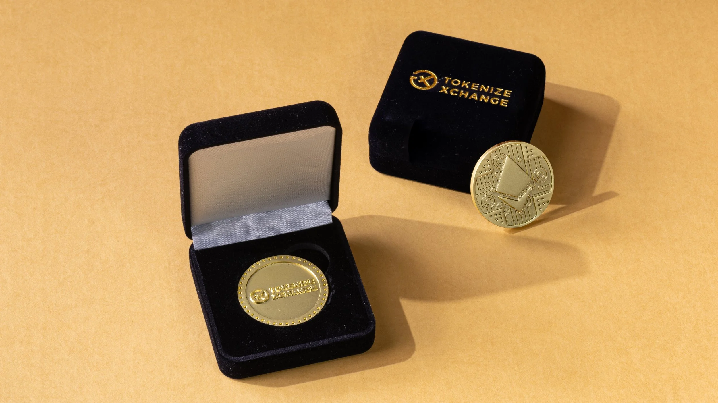 Gold Tokenize Xchange coin shown upright and inside its branded velvet presentation box