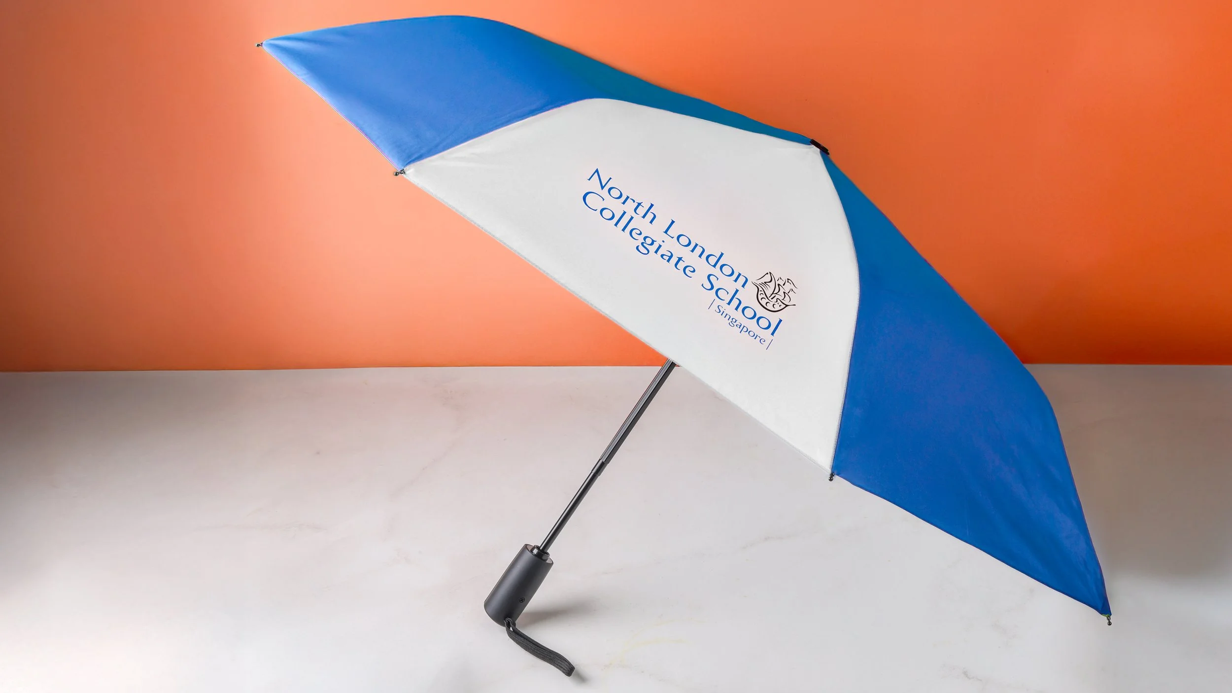 North London Collegiate School custom umbrella in blue and white with the school crest and wordmark
