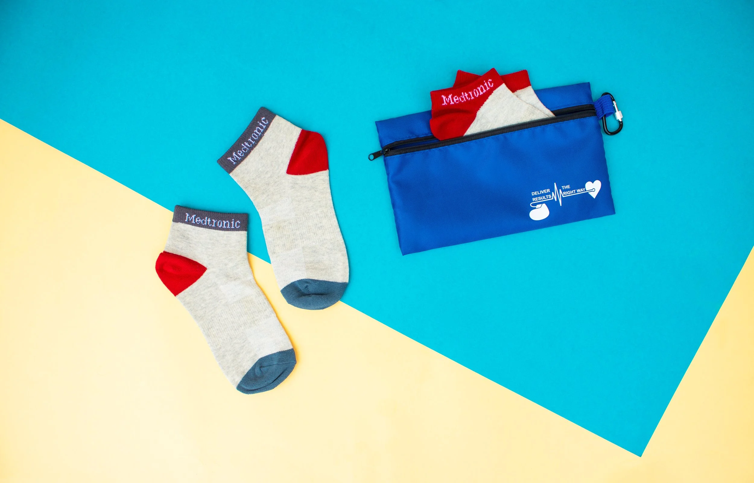 Grey and red custom ankle socks with a branded blue zip pouch and carabiner