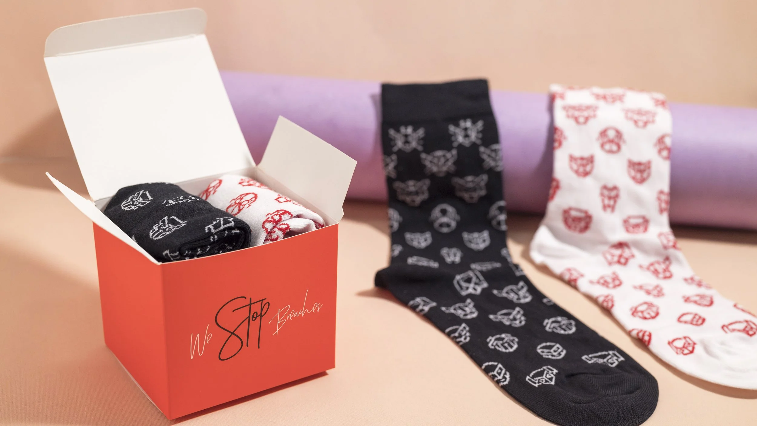 Black and white custom socks patterned with cybersecurity icons, in a branded gift box