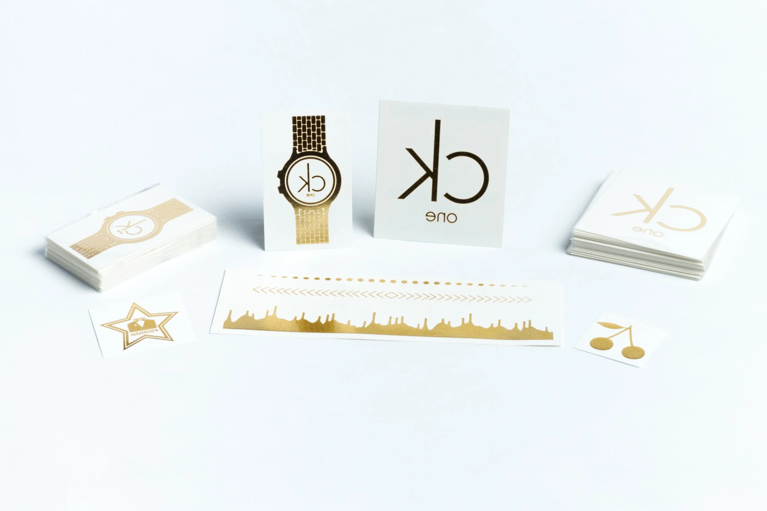 Gold foil metallic temporary tattoos including a watch design, logo sheets, star, cherries and a skyline band
