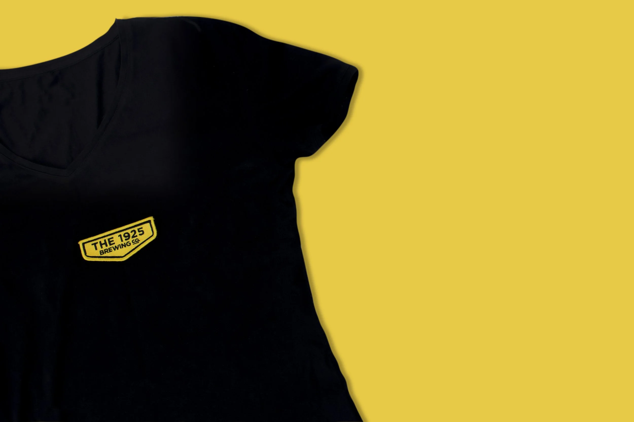 The 1925 Brewing Co logo patch in yellow and black applied to a black t-shirt