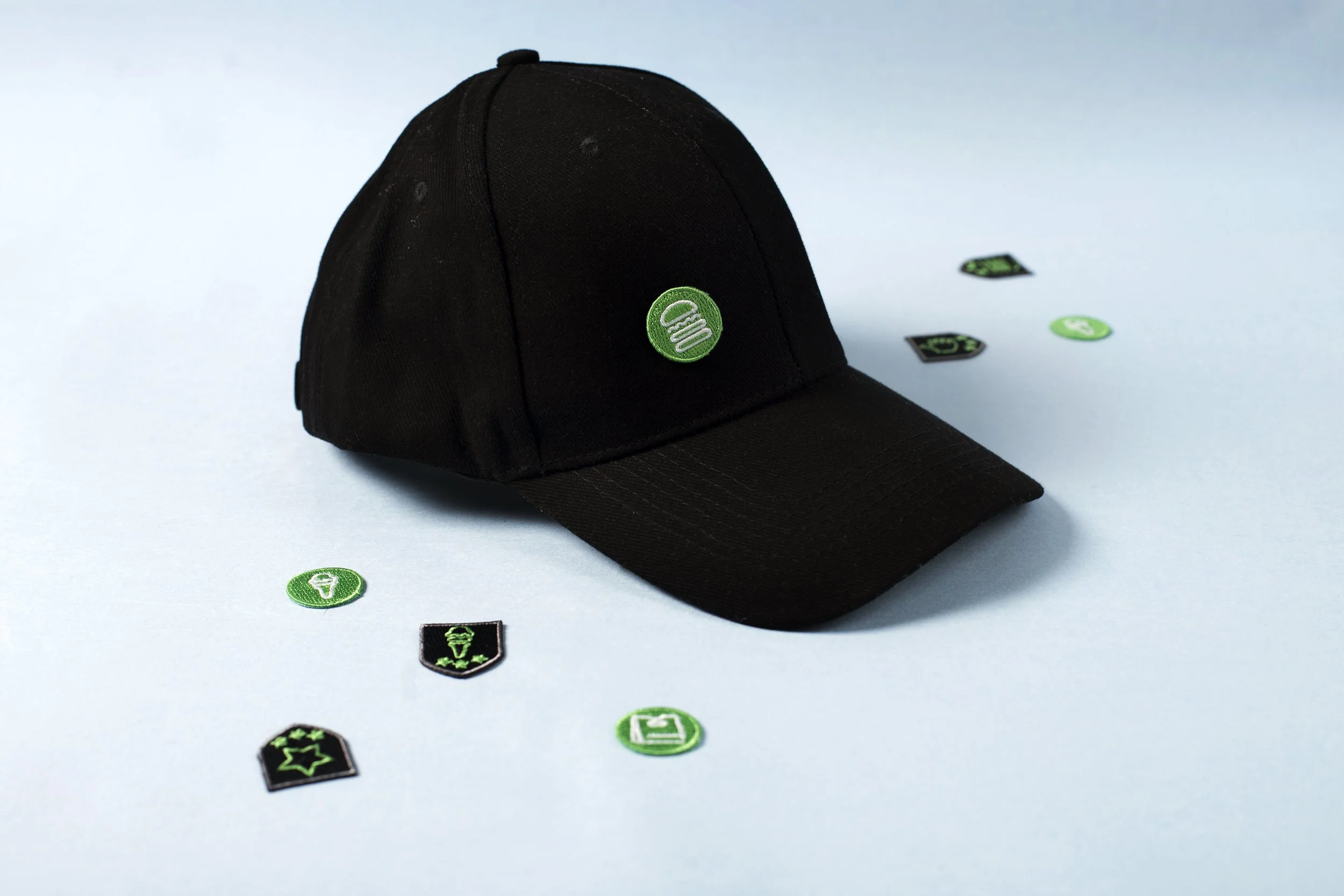 Shake Shack burger icon patch on a black baseball cap with a scattered set of matching icon patches