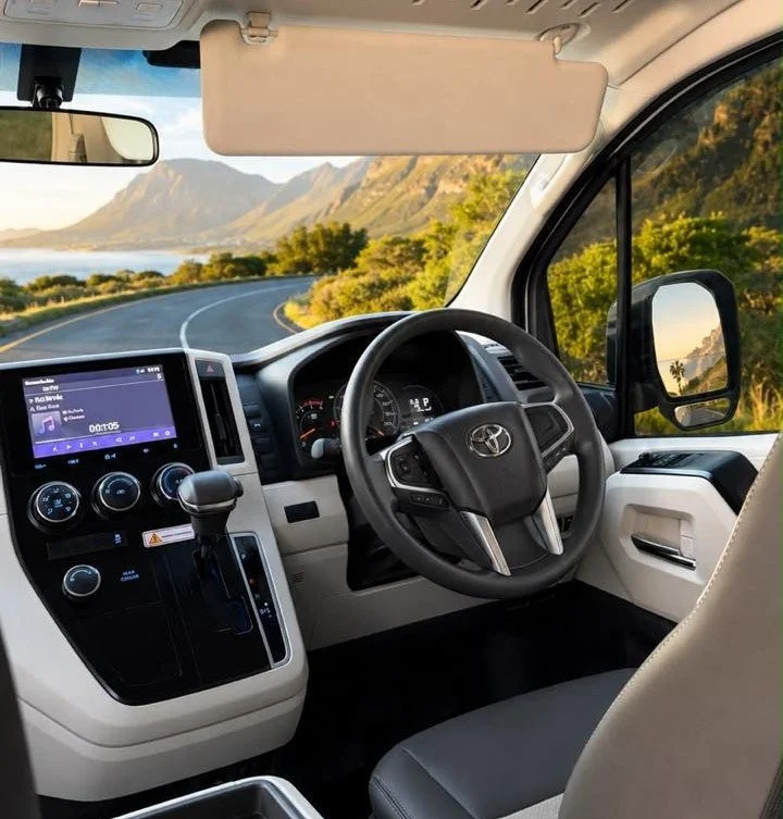 Inside a Toyota van with a scenic coastal road view through the windshield.