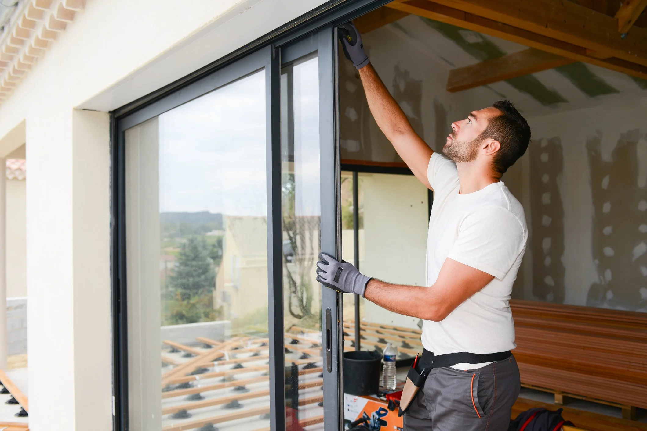 Handwerker montiert eine große Glasschiebetür in einem Haus.
