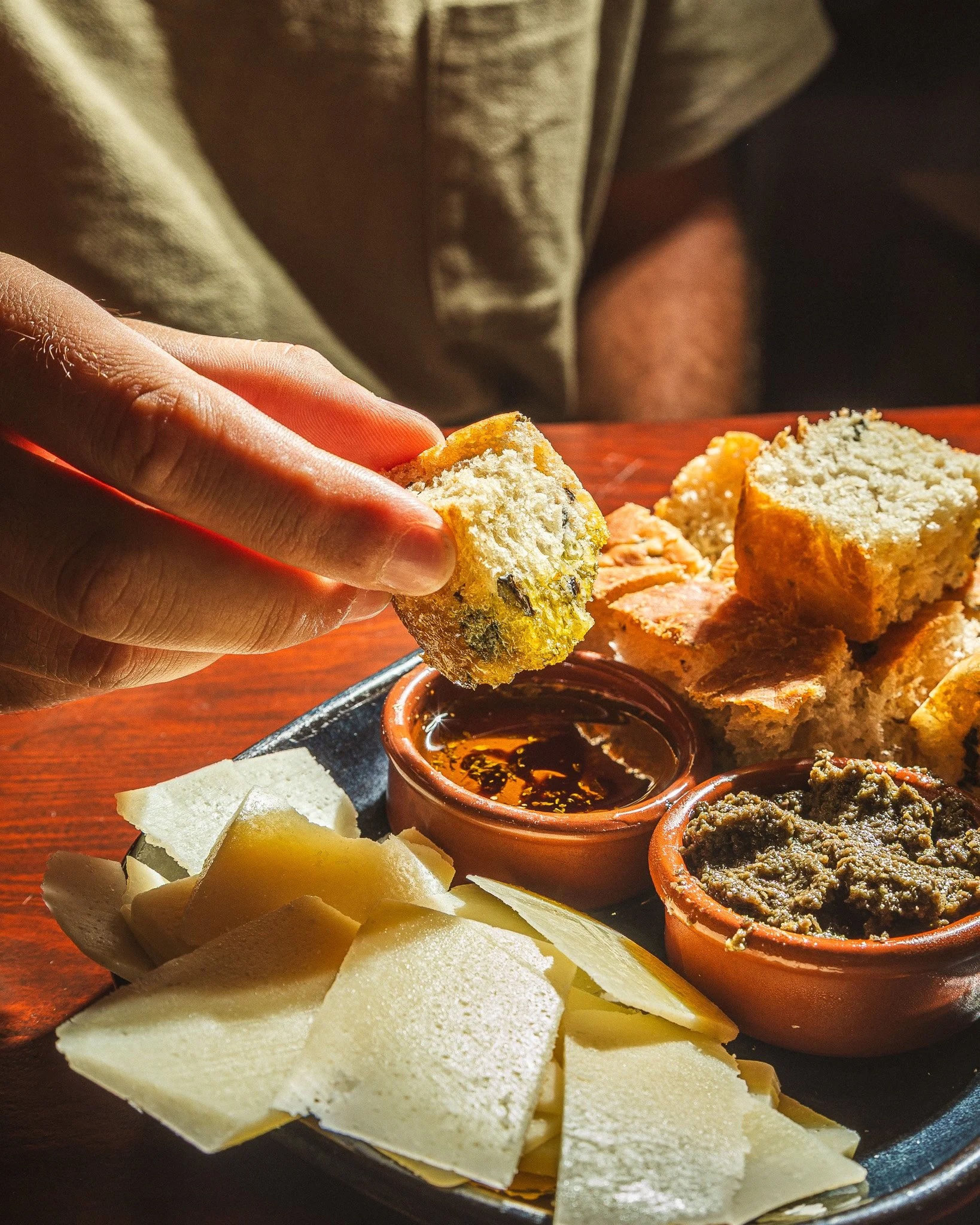 Porção de queijo branco fatiado, molho de pimenta, carne seca, queijo, pão e outros ingredientes típicos de petiscos brasileiros.