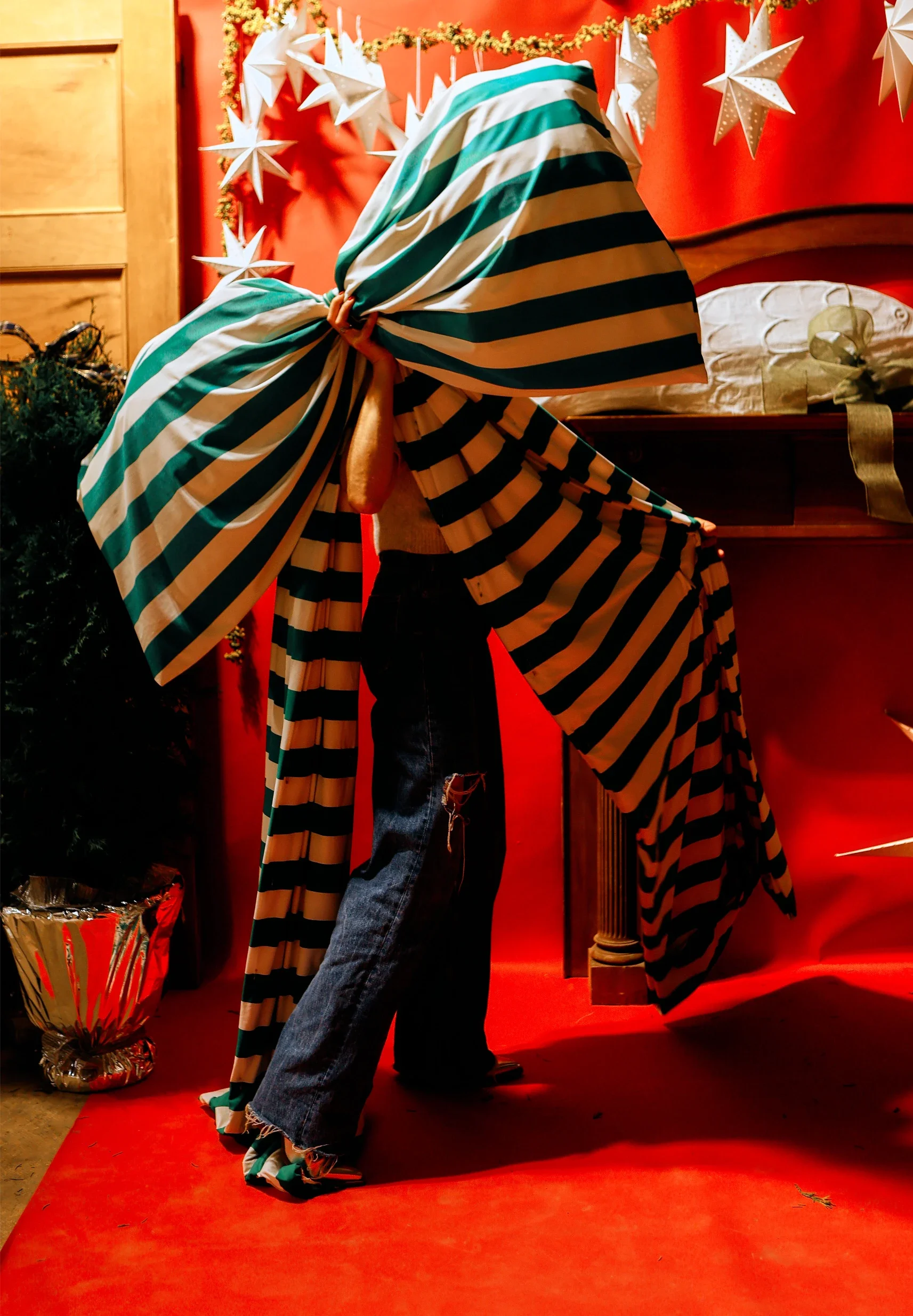 Guest wrapped in an oversized green and white striped bow at Wreath Bar