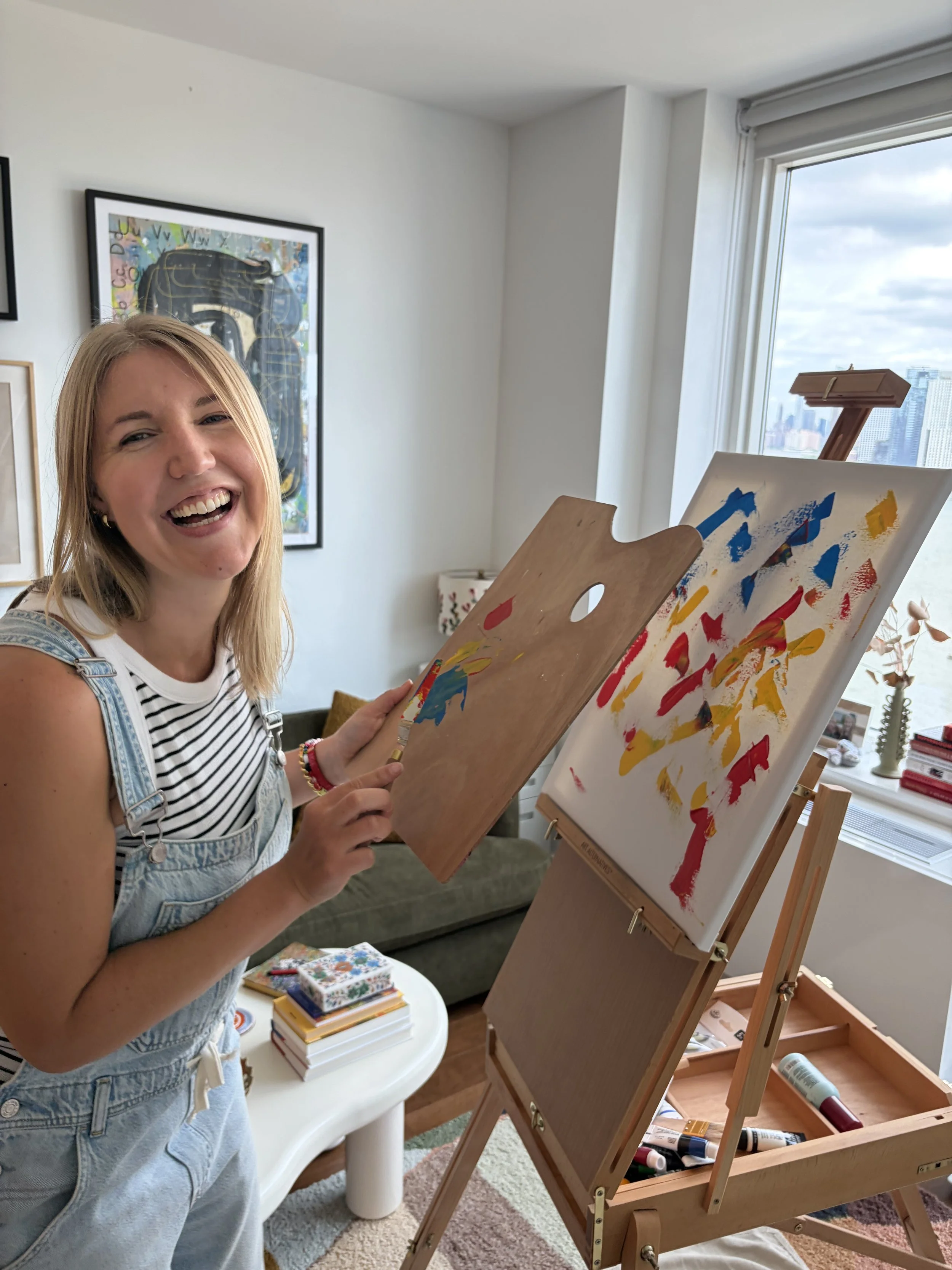 Summer Lindman laughing while painting at an easel.