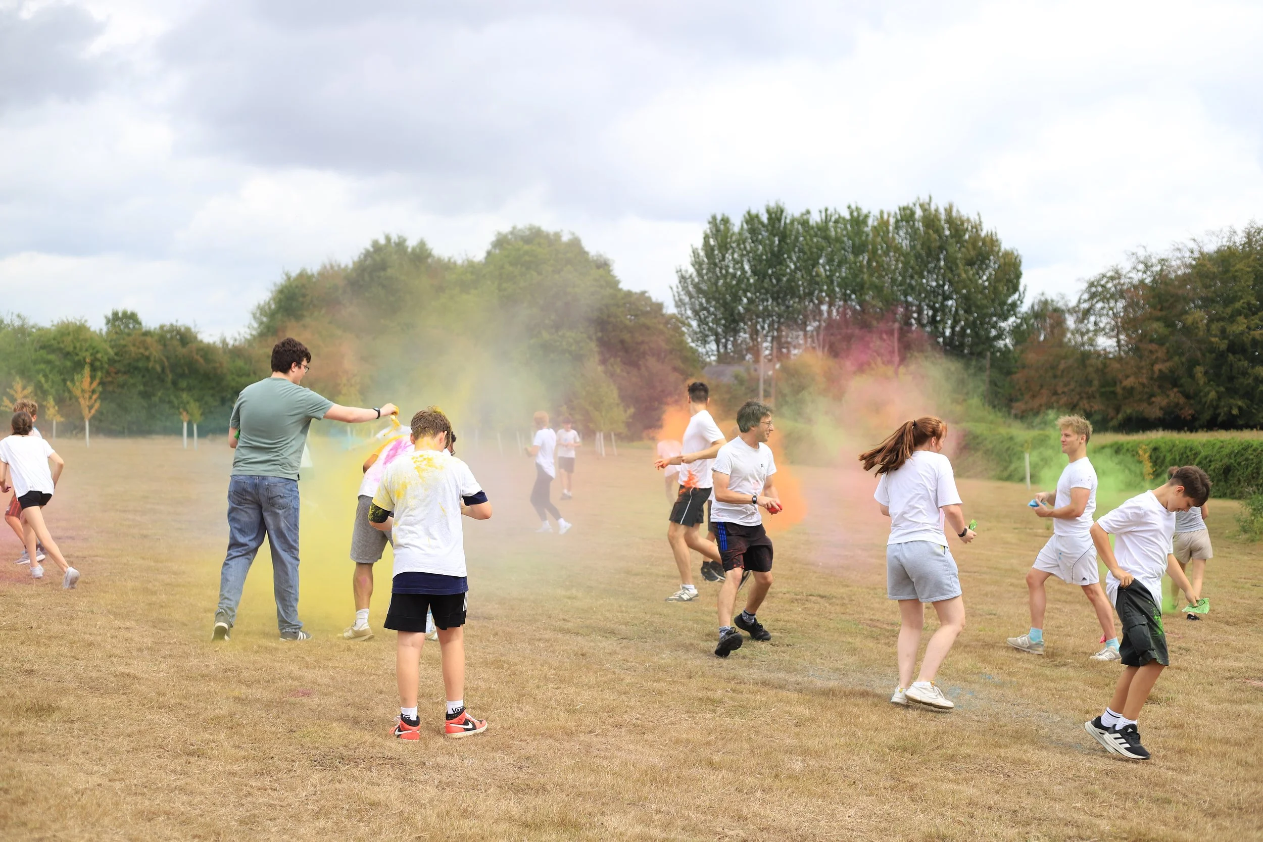 Group of teenagers throwing paint powder at each other.