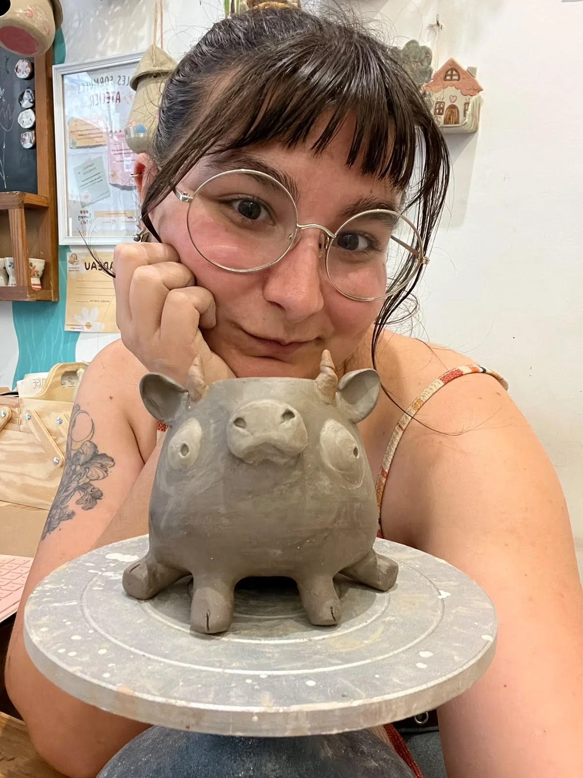 woman with bangs and round glasses seated behind a cute pottery bull