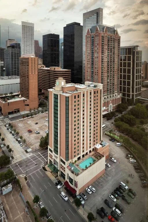 A city skyline featuring tall office buildings and a hotel with a rooftop pool in downtown.