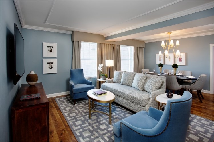 Living room with blue walls, a television, blue and beige furniture, a dining area, and decorative items.