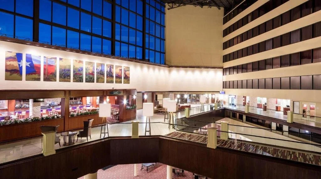 Interior of a hotel lobby with modern decor, large windows, artwork on the walls, and seating areas.