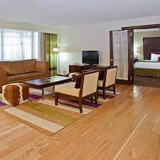 Living room with a brown sofa, two wooden chairs, a coffee table, a television, and a doorway leading to a bedroom.