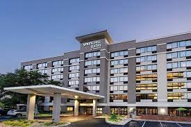 Exterior view of a modern, multi-story hotel building with a covered entrance and a sign reading 'Rochelle Hotel' on top.